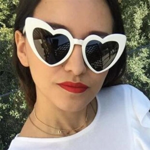Close-up of white heart-shaped sunglasses with dark UV400 lenses worn by a model