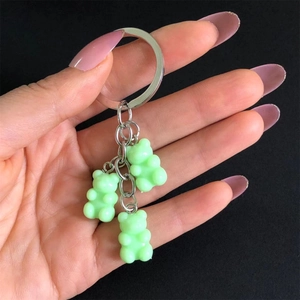 Close-up of green resin gummy bear charms on a silver metal keychain held by hand