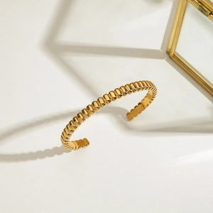 Détail de la texture perlée sur un bracelet jonc ouvert en acier inoxydable plaqué or poli