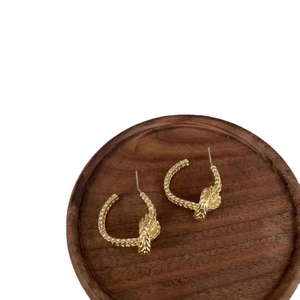 Retro twisted rope knot gold-plated C-shape hoop earrings on a dark wooden background