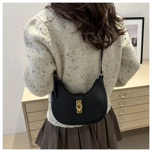 Detail of black crescent crossbody bag showing golden metal buckle and PU leather texture