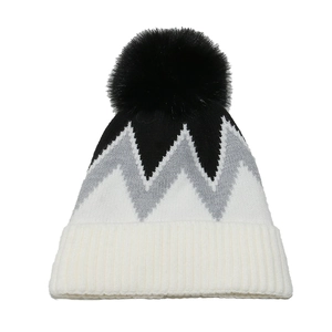 Dettaglio del cappello invernale in maglia con motivi a onde e pompon nero in ecopelliccia