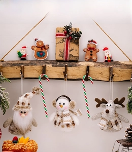 Detailed view of plush Santa, Snowman, and Reindeer ornaments on a rustic branch