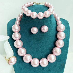 Elegant pink pearl jewelry set featuring necklace bracelet earrings and ring on mannequin