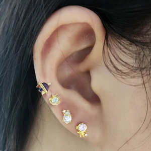 Detailed view of set of four gold-plated silver cartilage studs with cosmic and alien motifs