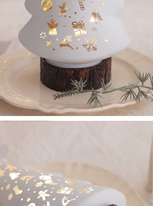 Close-up of white Christmas tree ceramic decor with gold holiday patterns and wood base