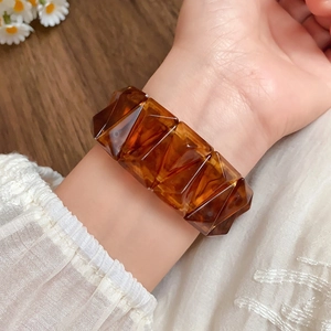 Detail of amber acrylic faceted pyramid stretch bracelet on a woman wrist with lace