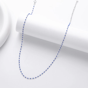 Detail of s925 silver chain necklace featuring small blue beads on a white pedestal