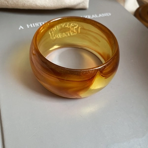 Macro detail of amber resin bangle showing fluid texture and internal engraving