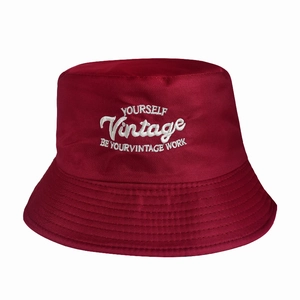 Detail of vintage white embroidery on a wine red cotton bucket hat with clean stitching