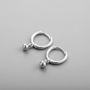 Gros plan de créoles en argent poli avec breloques sphériques minimalistes
