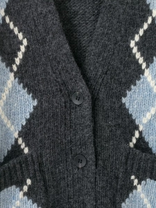 Detail showing the thick argyle knit texture with grey and blue patterns and black button