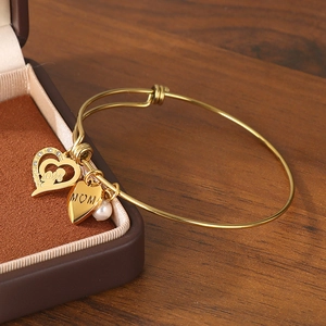 Detail of adjustable gold MOM heart bracelet with pearl and crystal charms on jewelry box