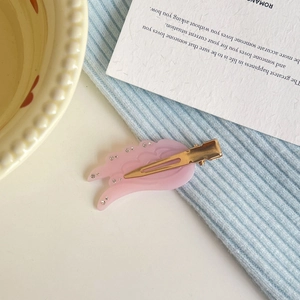 Pink wing-shaped hair clip with small white rhinestones and a gold metal claw