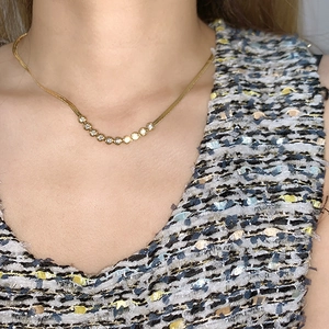 Close-up of golden titanium snake chain necklace with a curved zircon pendant on a model