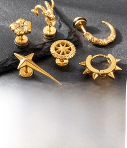 Detailed close-up of gold titanium steel punk earrings including goat head and spikes