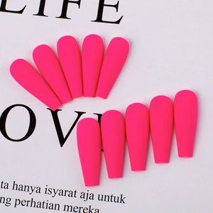 Detailed view of pink matte long coffin press-on nails arranged on a printed paper