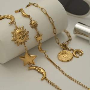 Detail of 18k gold stainless steel bracelet featuring star, moon and coin charms