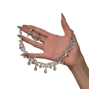 Silver teardrop jewelry set with necklace and earrings displayed on hand