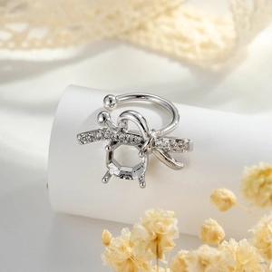 Silver bow ear cuff with sparkling rhinestones and a four-prong setting on a prop