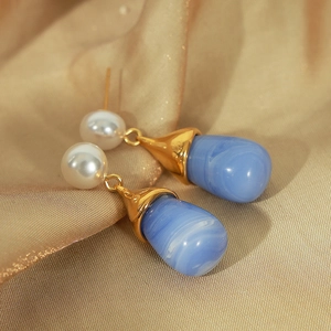 Gold plated teardrop earrings with blue marble resin and pearls on silk background