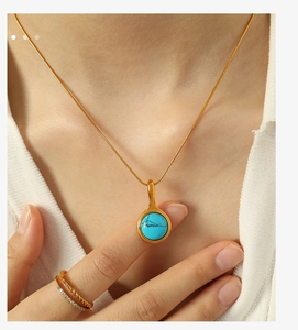 Close-up of gold chain necklace with turquoise pendant on a model's neck
