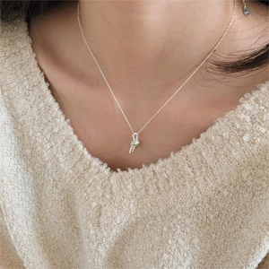 Detailed view of S925 sterling silver knotted pendant necklace worn on a beige sweater