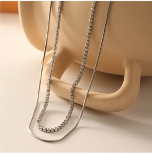 Gros plan d'un collier double épaisseur en argent avec gemmes sur une anse en céramique