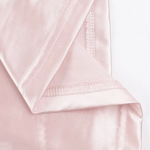 Detailed macro view of smooth light pink satin fabric and premium sewing stitching edges