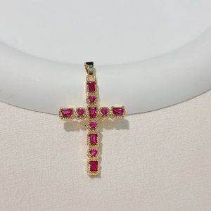 Detailed view of gold plated cross pendant with red gemstones and beaded texture edges
