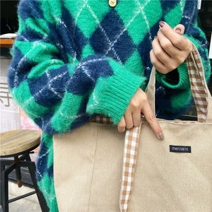 Detail of beige canvas tote bag with brown gingham handle and merciparis woven label