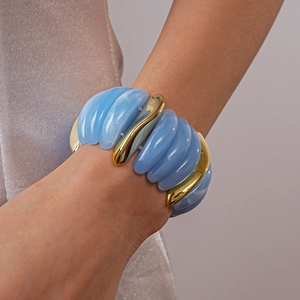 Close-up of chunky sky blue resin beads and polished gold metal segments on a wrist
