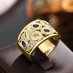 Détail d'une large bague dorée vintage sertie de pierres bleues et reliefs floraux