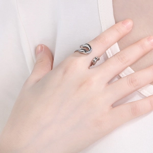Detail view of silver liquid metal open ring with abstract flowing design on finger