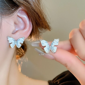 Detailed view of elegant silver butterfly earrings with blue stone and inlaid crystals