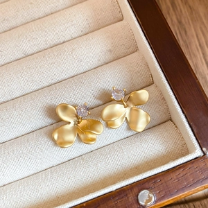 Detail of matte gold floral earrings with sparkling cubic zirconia in a jewelry box