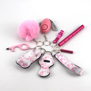 Detail of pink keychain set with pompom, alarm, and marble patterned sanitizing bottle