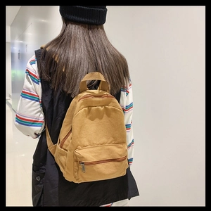 Seitenansicht eines khakifarbenen Canvas-Rucksacks, getragen von einem Modell innen