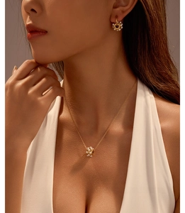 Détail d'un ensemble collier et boucles d'oreilles en perles sur modèle en robe blanche