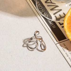 Close-up of a silver minimalist streamlined open ring displayed with an orange slice