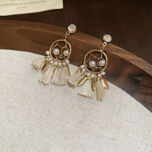 Bohemian dreamcatcher earrings with white pearls and tassels on a wooden tray
