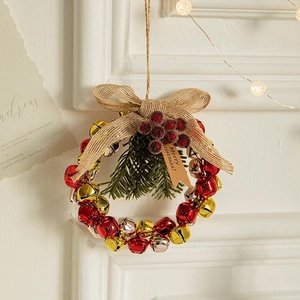 Christmas wreath with colorful bells, burlap bow, pine needles and berries hanging on wall