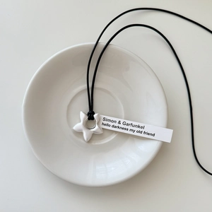Macro detail of star-shaped brushed silver pendant with Simon & Garfunkel lyric engraving