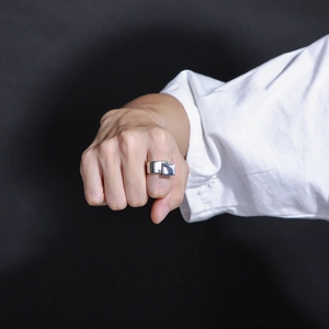 Anello quadrato in argento lucido da uomo indossato sulla mano su uno sfondo nero