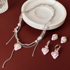 Detailaufnahme des Erdbeerschmuck-Sets mit Herzanhängern und Perlen auf weißem Teller