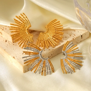 Detail of fan-shaped stainless steel earrings in gold and two-tone finishes on silk