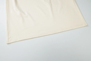 Detailed close-up of cream knit maxi dress hem with double-stitch sewing finish