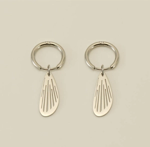 Close-up of silver hollow wing pendant earrings with sleek metallic finish and linear detail