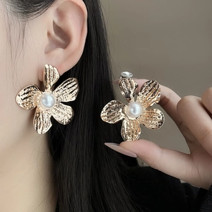 Close-up of vintage golden flower earrings with pearls worn by a model in detail