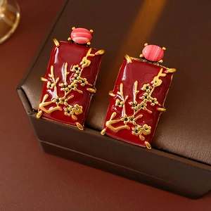 Vue macro détaillée de boucles d'oreilles vintage en émail rouge à motif floral doré